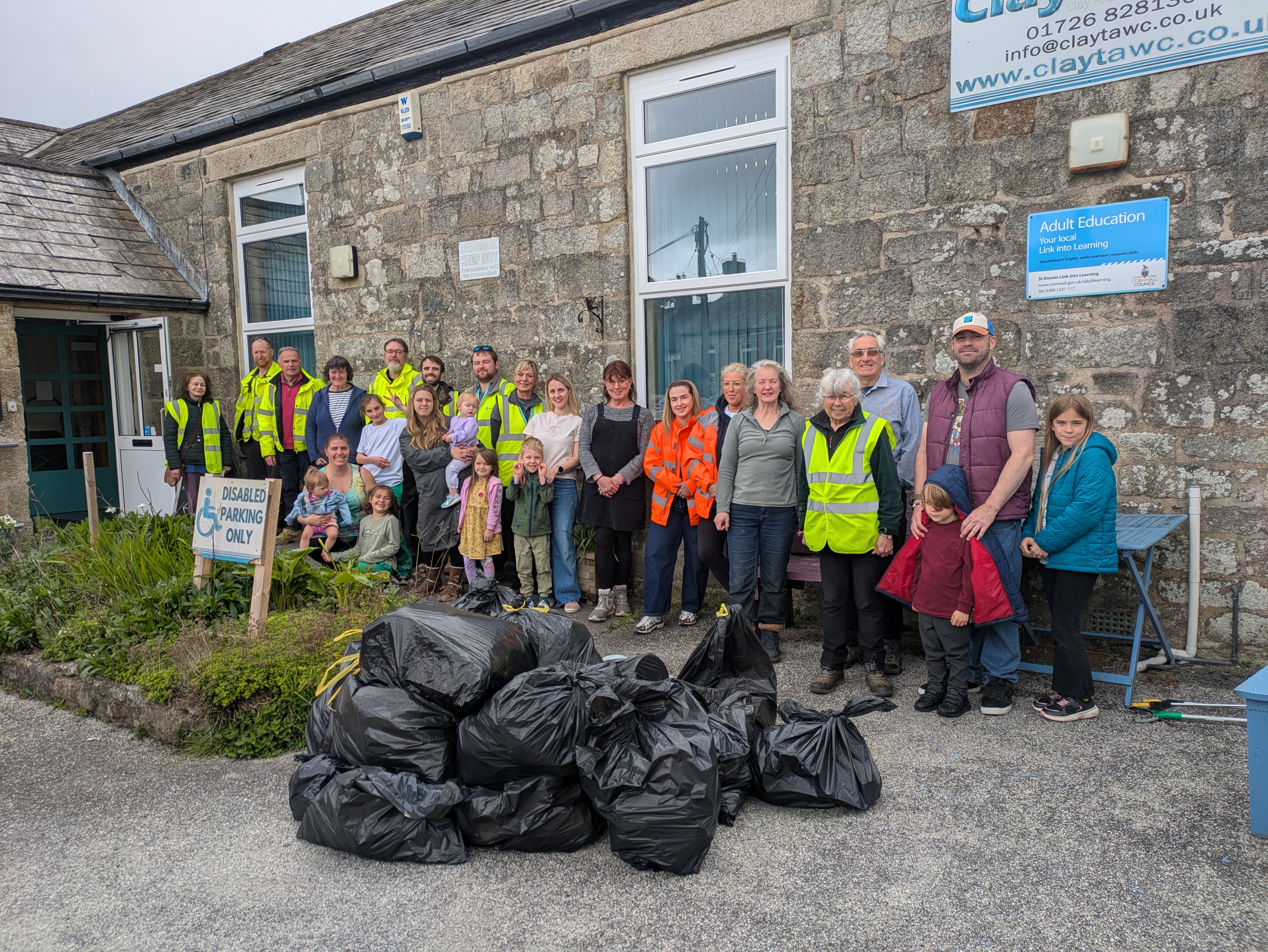 Group of volunteers stood in front of ClayTAWC with a large pile of black bags filled with rubbish in the forground